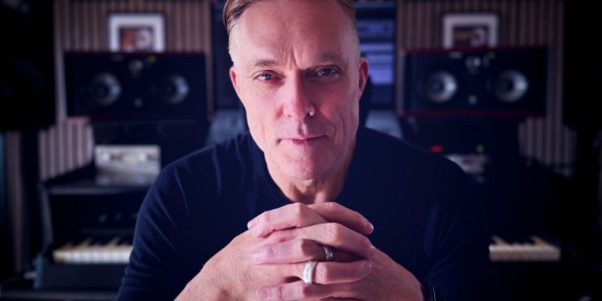 Candid studio photograph of ambient and trance artist Nicholas Gunn creating electronic music, surrounded by synthesizers used to produce his signature melodic house and chillout tracks.